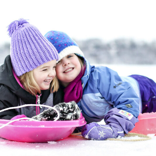 Girls on Sled 2 little girls on sleds in the snow laughing